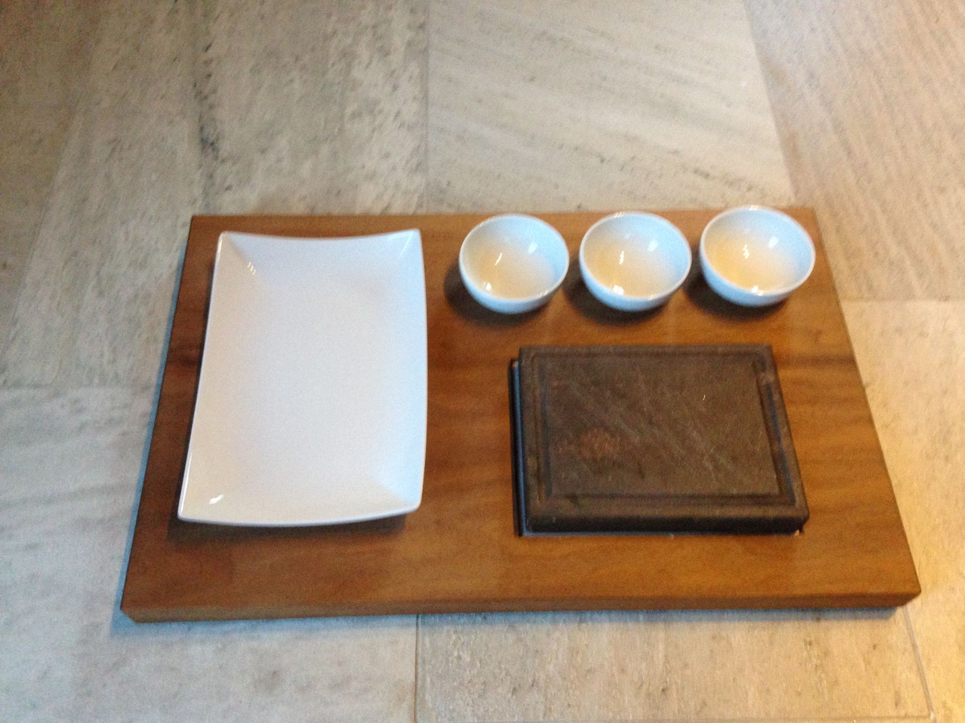 A wooden cutting board with three white bowls on it