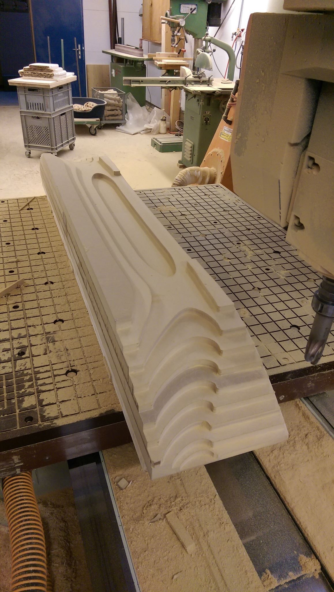 A piece of wood is being cut on a machine in a workshop.