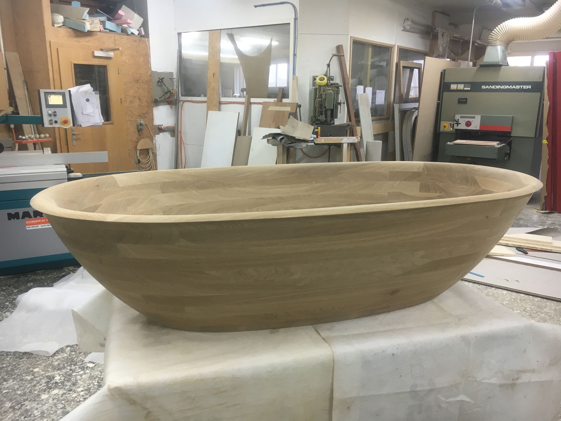 A large wooden bowl is sitting on a table in a workshop.