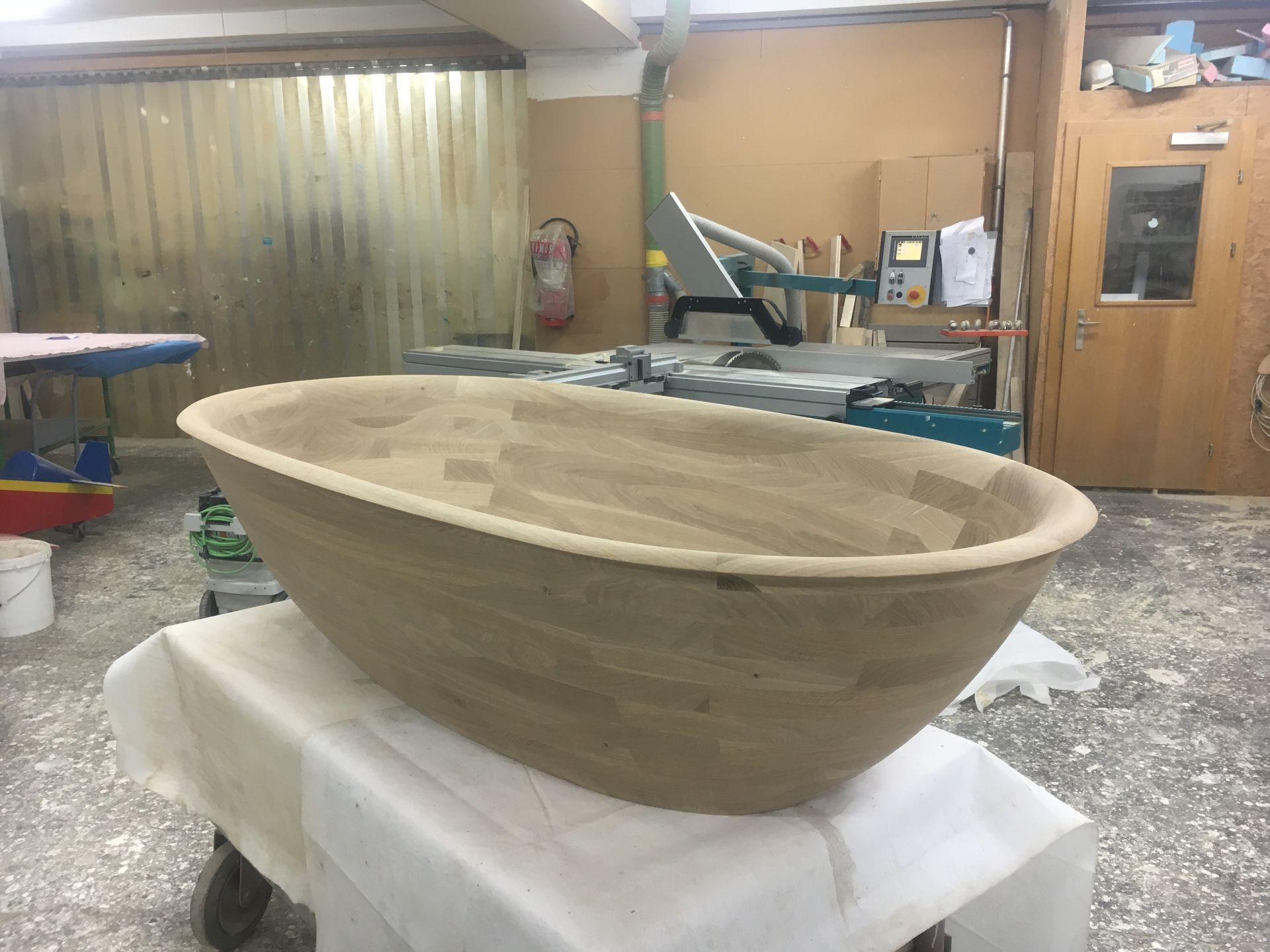A large wooden bowl is sitting on a table in a room.