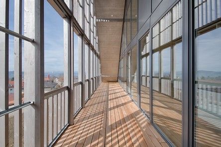 A long hallway with a lot of windows and a wooden floor.