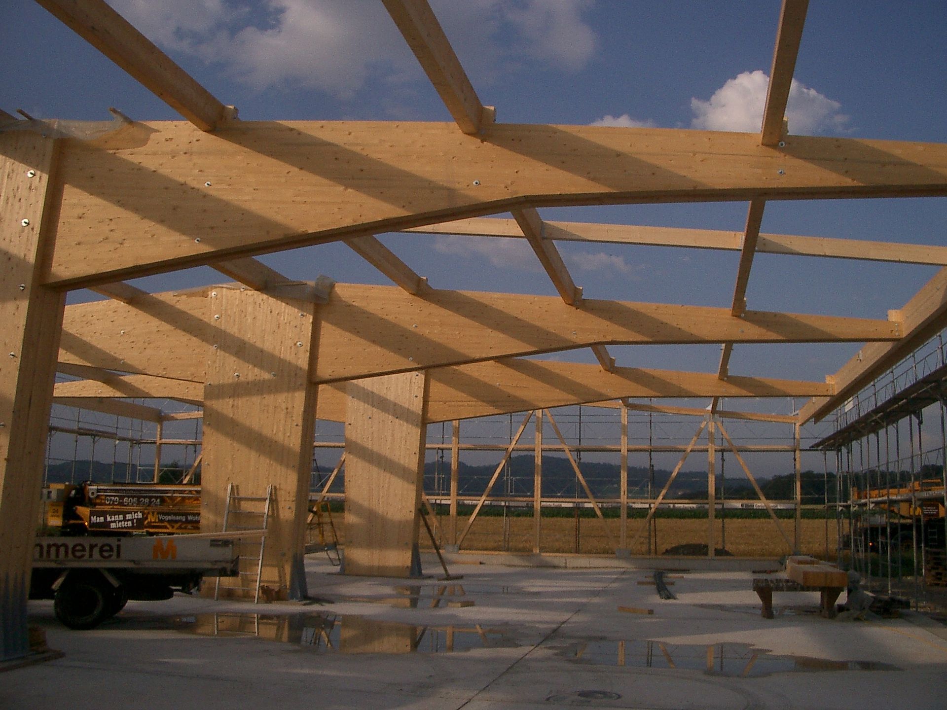 A large wooden structure is being built with a truck parked in front of it