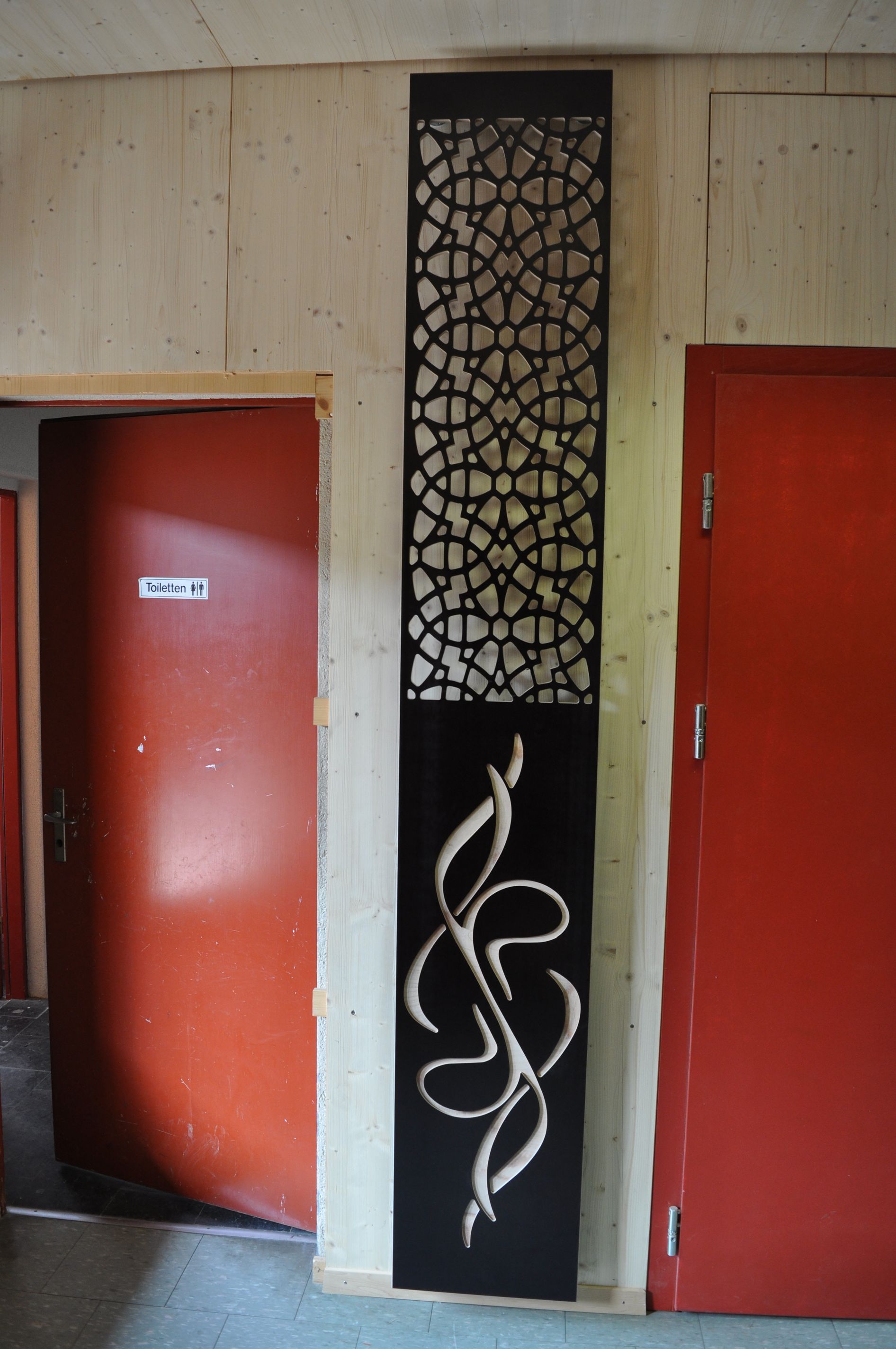 A snake is carved into a wall next to a red door