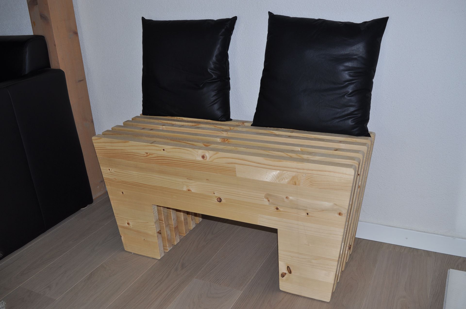 A wooden bench with two black pillows on it