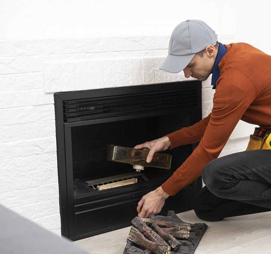 Un hombre está arrodillado frente a una chimenea.