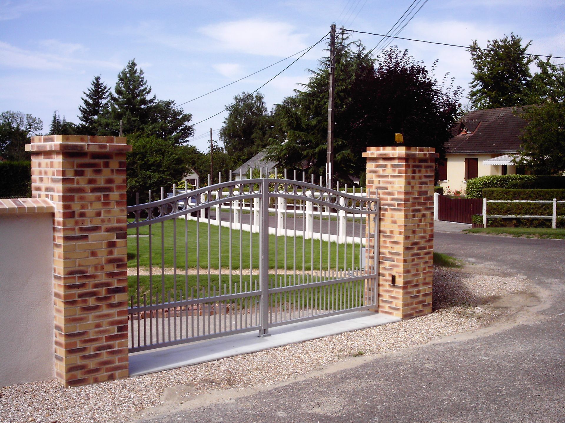 Portail avec des barreaux gris et des piliers en pierre