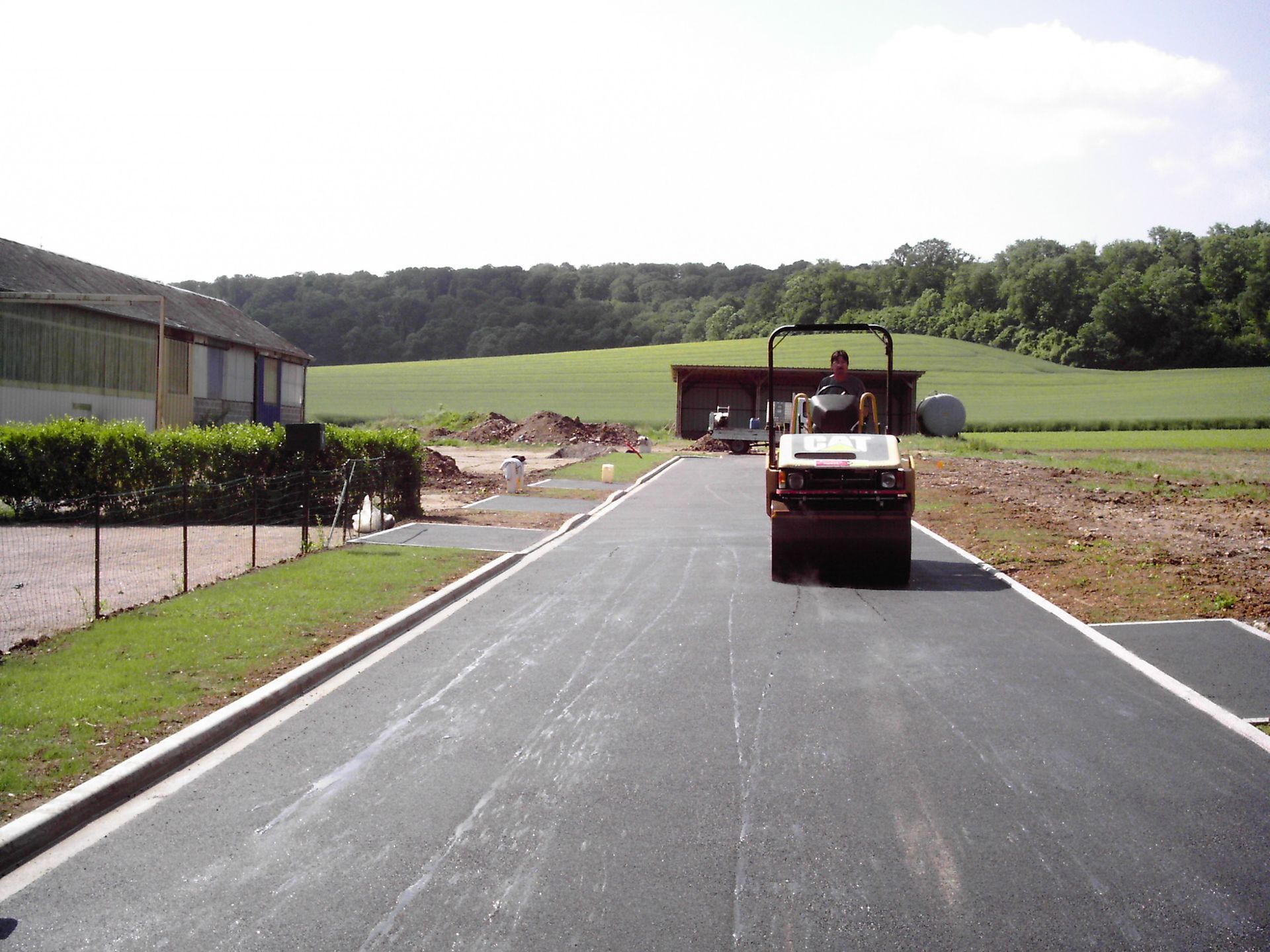 Un ouvrier utilise un rouleau compresseur sur une route en béton