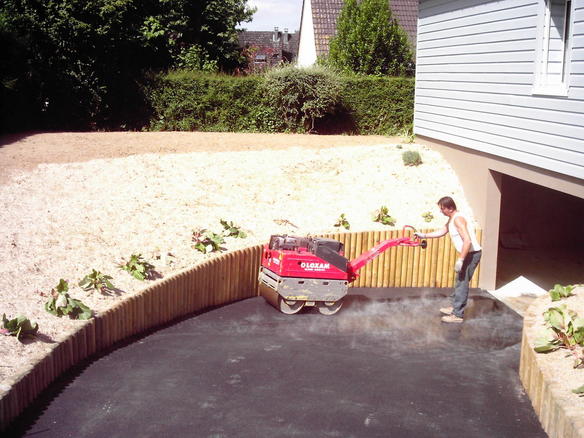 Un ouvrier utilise un rouleau compresseur sur une allée de garage en béton