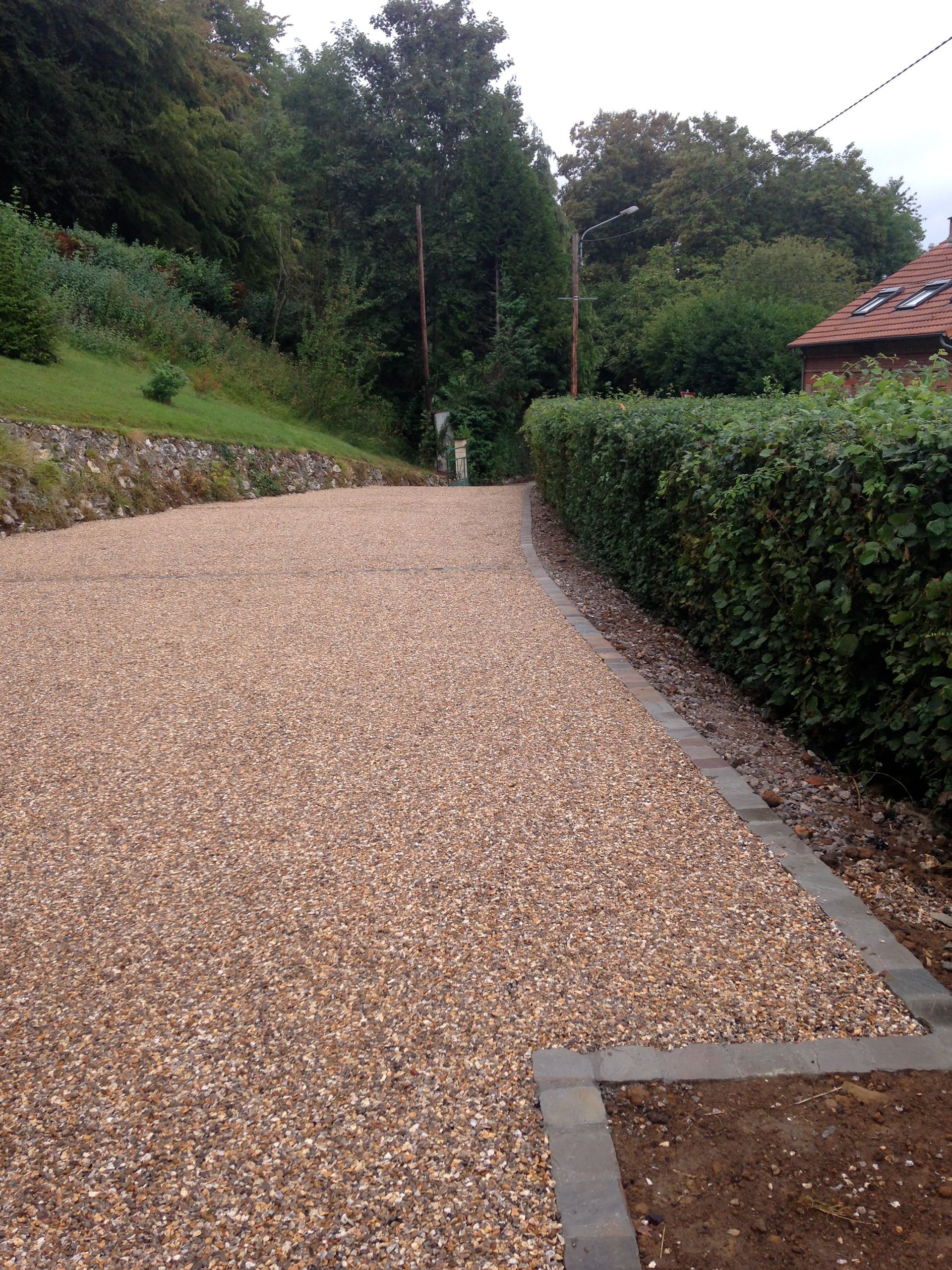 Une allée en émulsion gravillonnée avec une haie