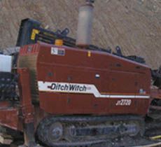 Un tractor rojo está estacionado en un camino de tierra.