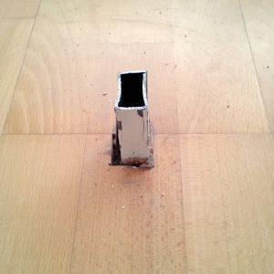 Quadratischer Metallpfosten im Holzboden.