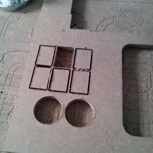 Ein Stück Holz mit ausgeschnittenen rechteckigen und kreisförmigen Formen, möglicherweise für ein Projekt.