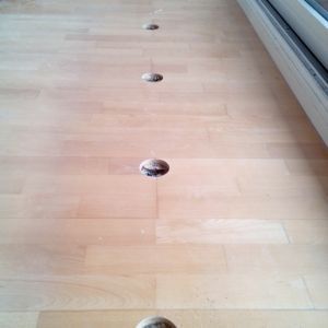 Holzboden mit mehreren gleichmäßig verteilten Löchern.