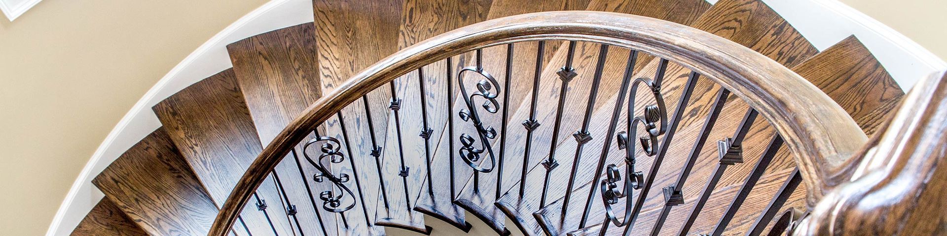 Hölzerne Wendeltreppe mit verziertem schwarzen Geländer.