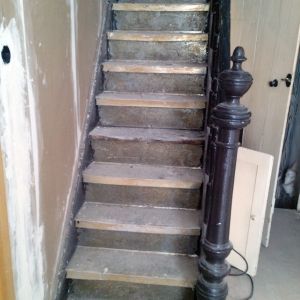 Betontreppe mit dunklem Holzgeländer in einem Innenraum.