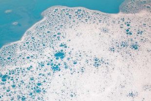 Weiße Blasen auf blauem Wasser, wahrscheinlich ein Bad.