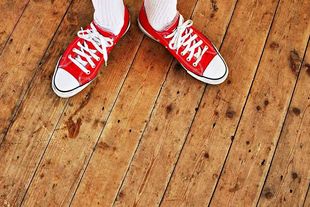 Rote Turnschuhe und weiße Socken auf einem Holzboden.