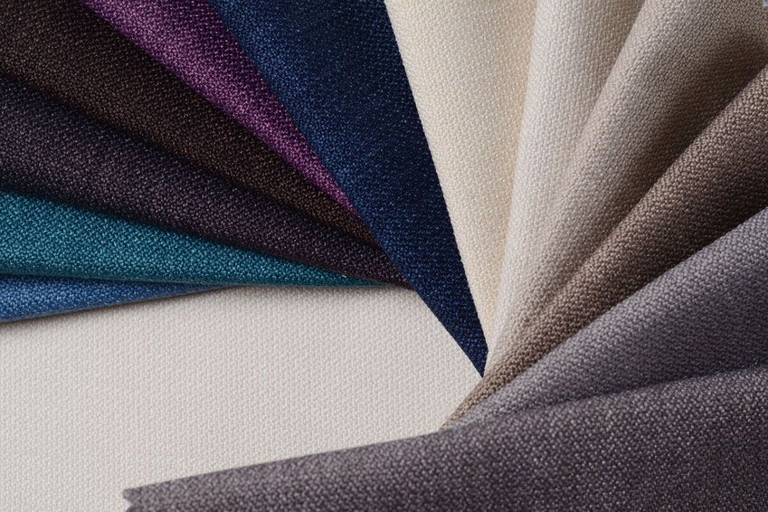 Stoffmuster in verschiedenen Farben, darunter Blau, Lila, Beige und Grau.