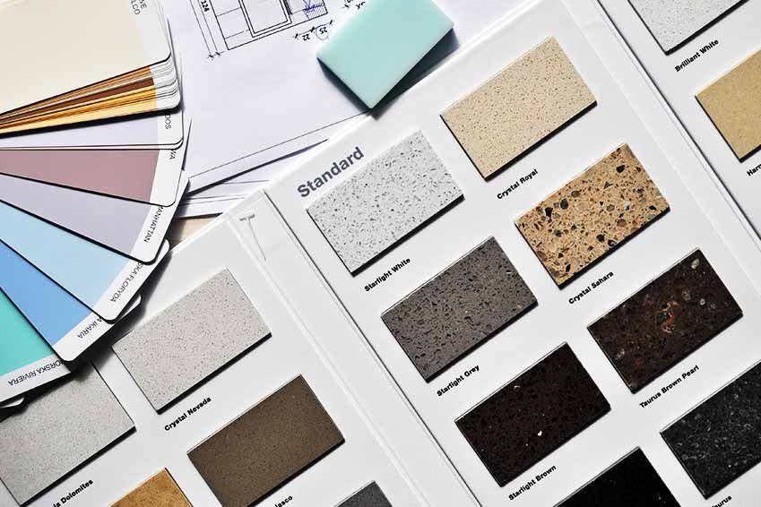 Farbmuster, Arbeitsplattenmuster und Baupläne auf einem Tisch präsentieren Design- und Materialoptionen.
