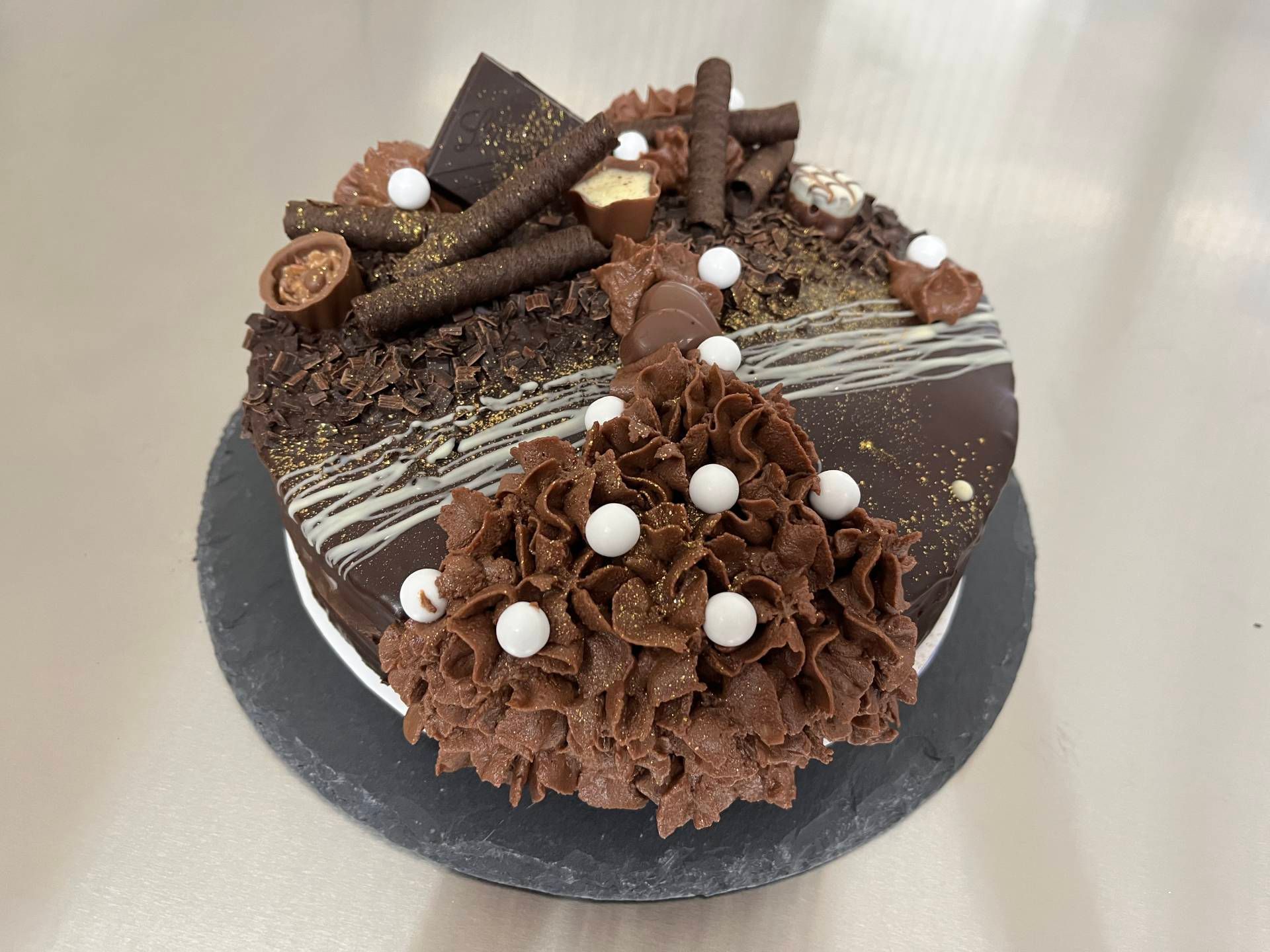 Schokoladenkuchen mit Schokoladenlocken und weissen Bonbons auf einem schwarzen Ständer
