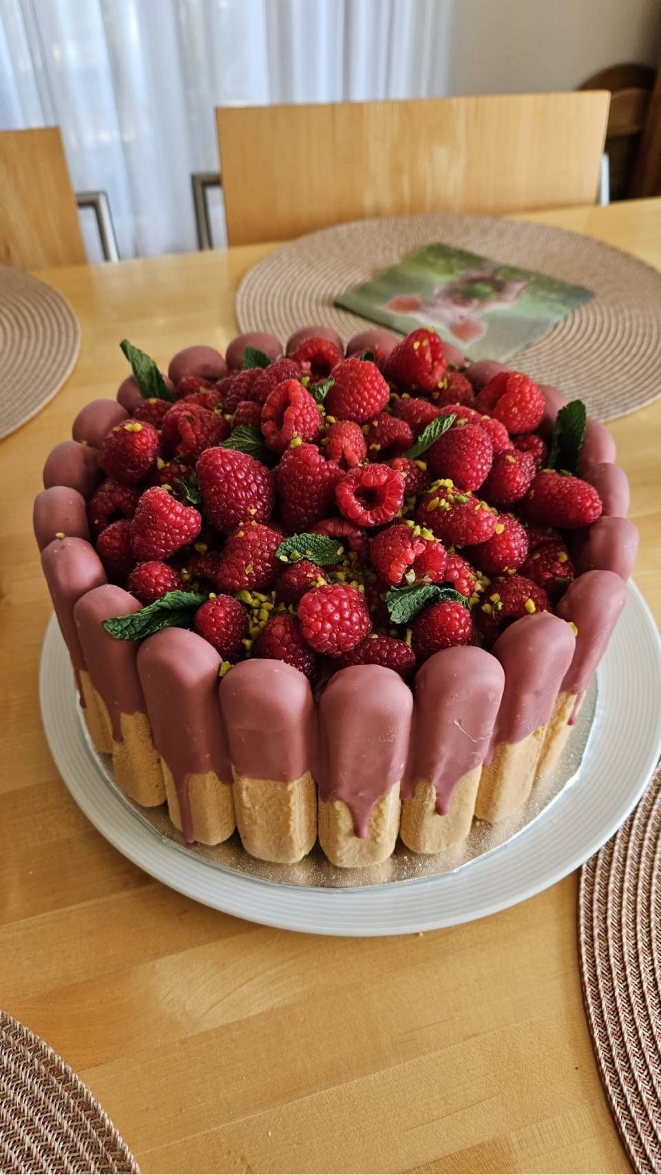 Erdbeertorte auf einem weissen Teller, dazu Löffelbiskuits auf einem Holztisch.
