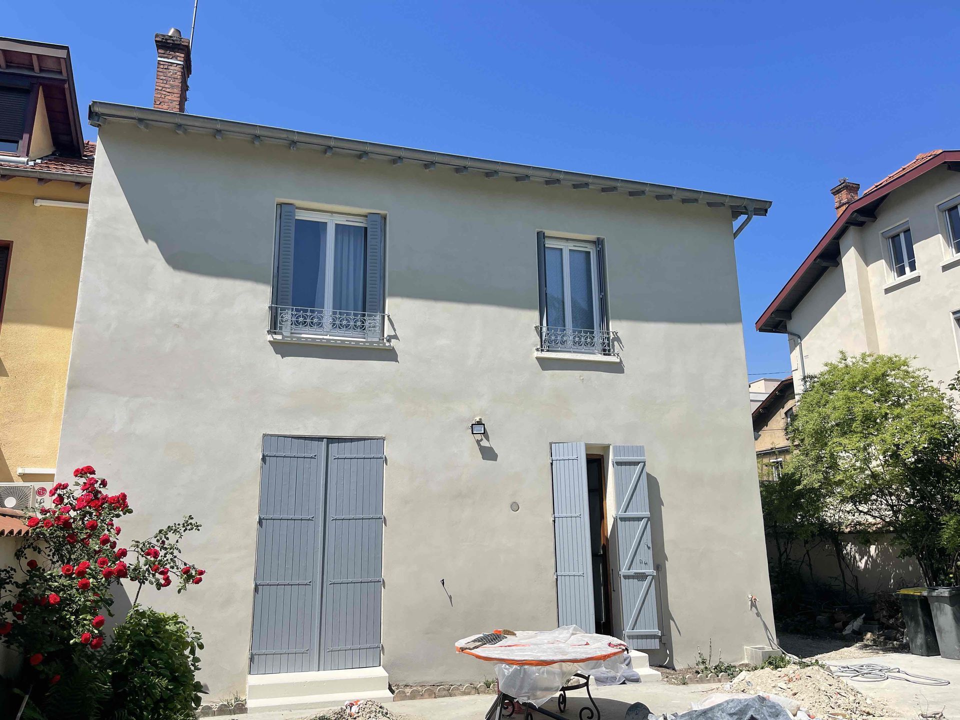 Façade d'une maison peinte à la chaux avec les volets gris