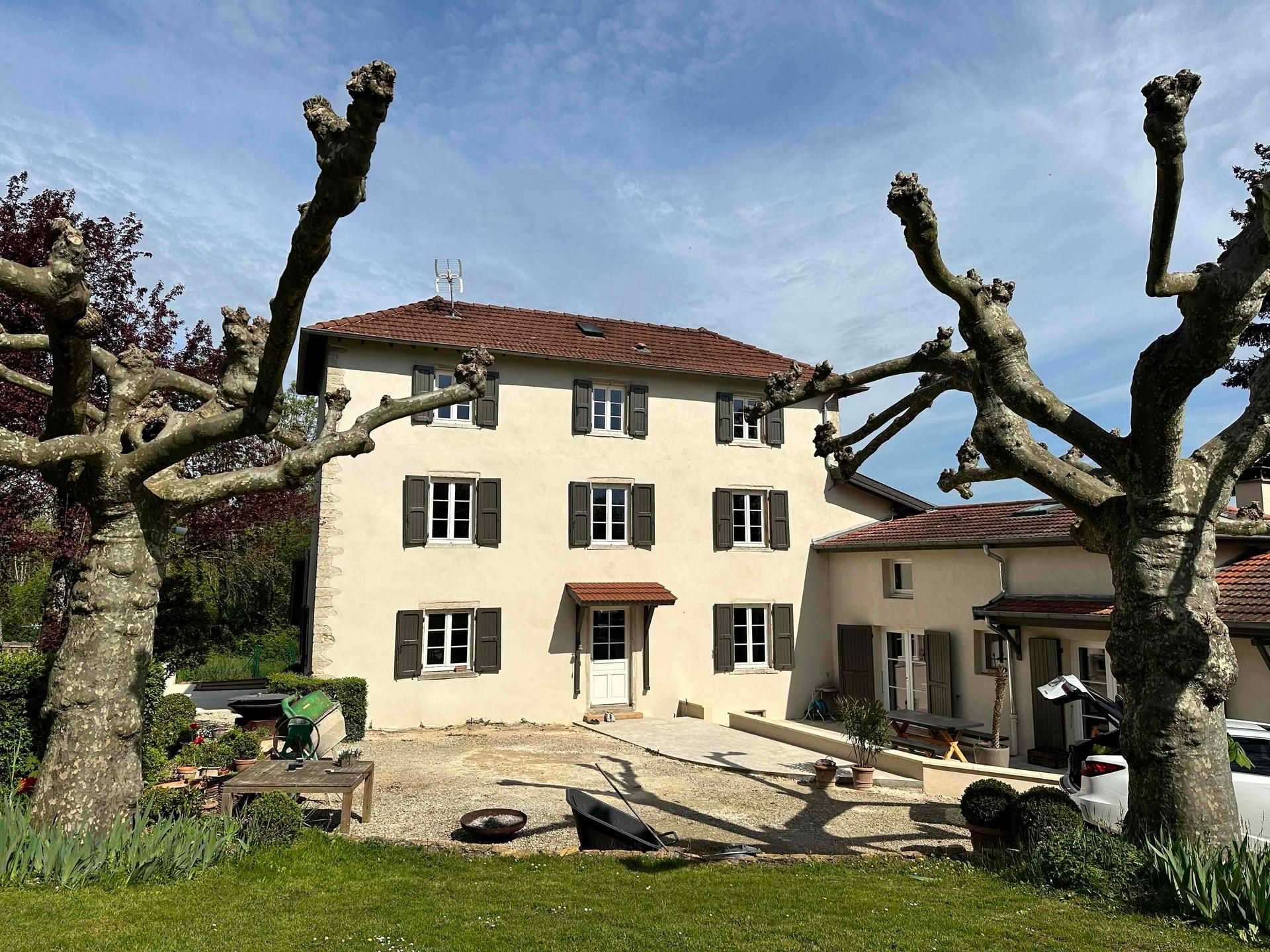 Maison avec des volets marron et une façade peinte à la chaux