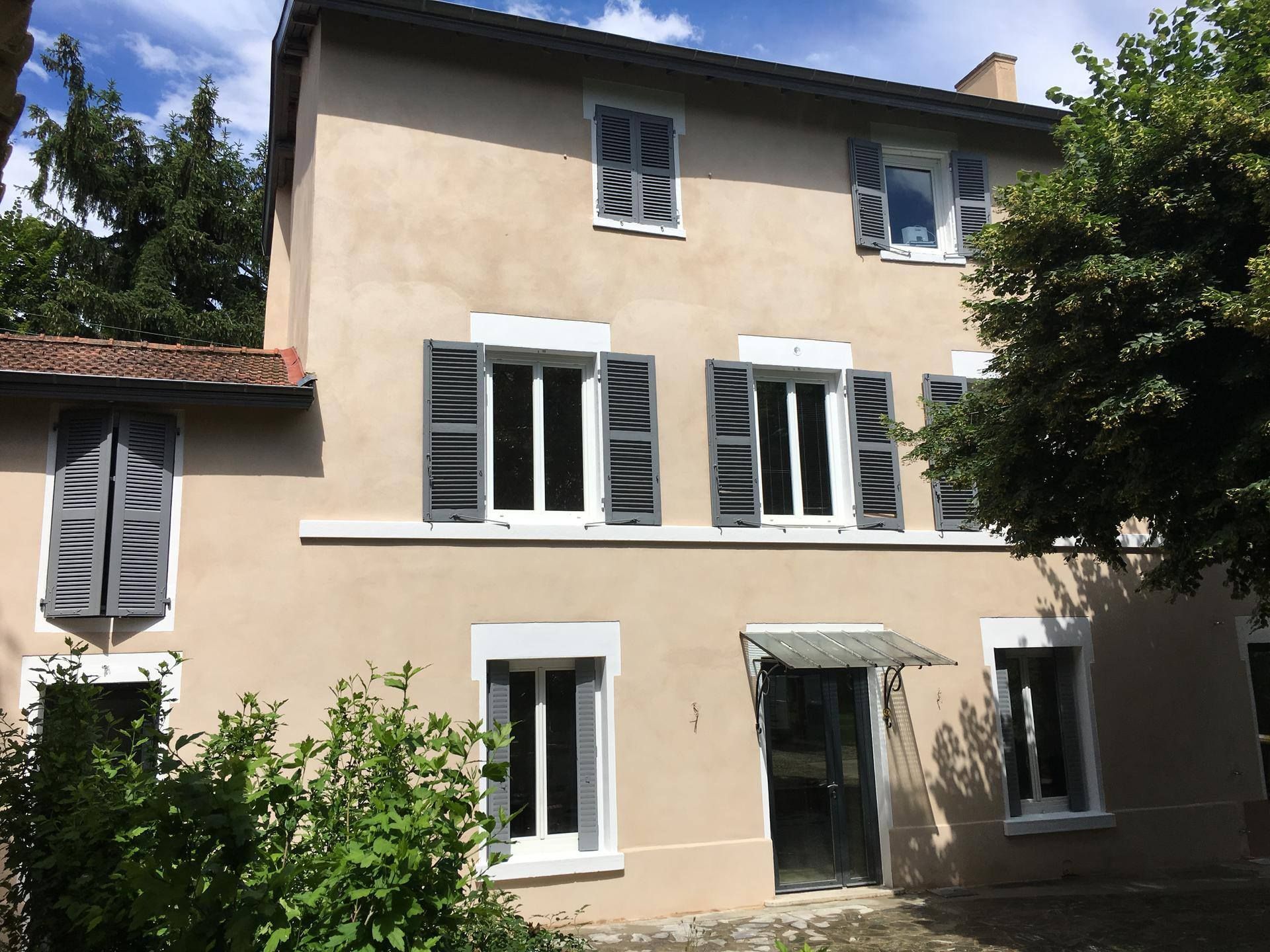 Façade de maison peinte à la chaux, volets gris