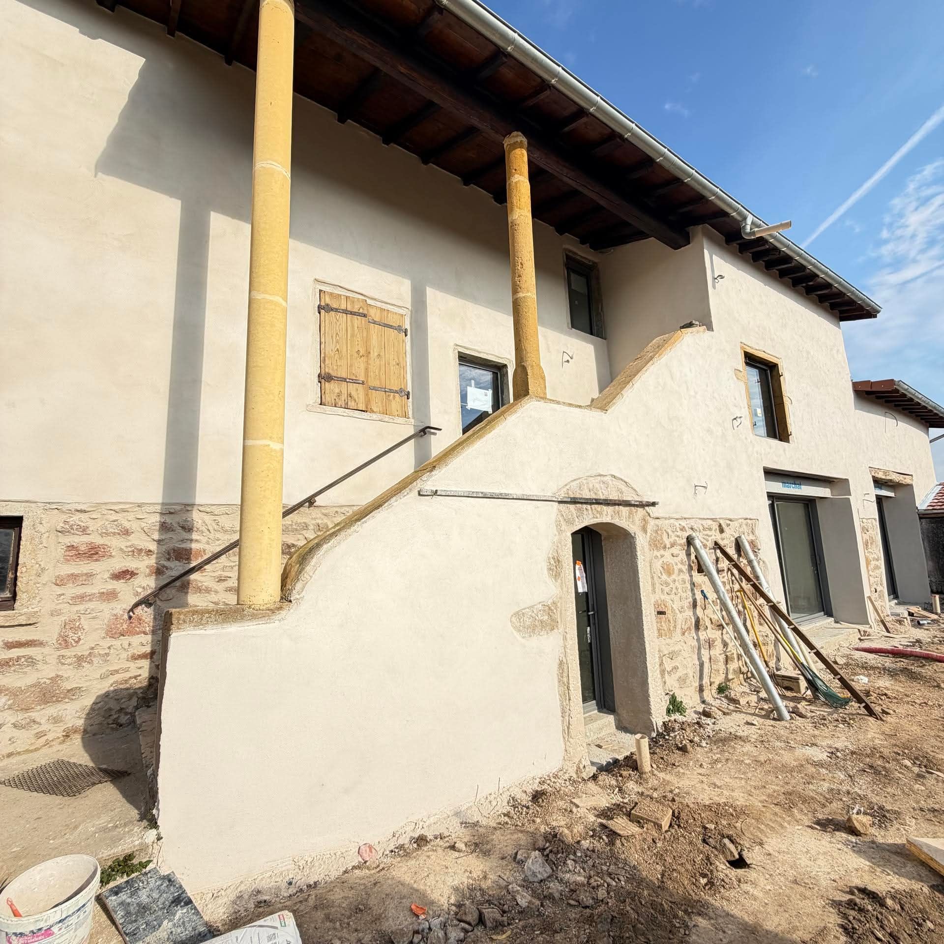 Maison ancienne en pleine rénovation avec enduit de façade et soubassement en pierre
