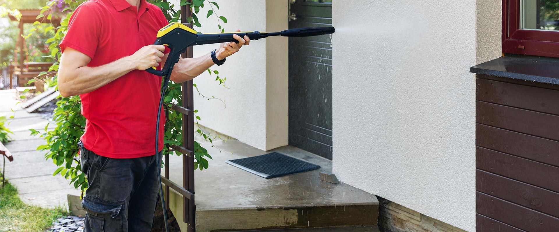 Homme qui nettoie la façade d'une maison neuve