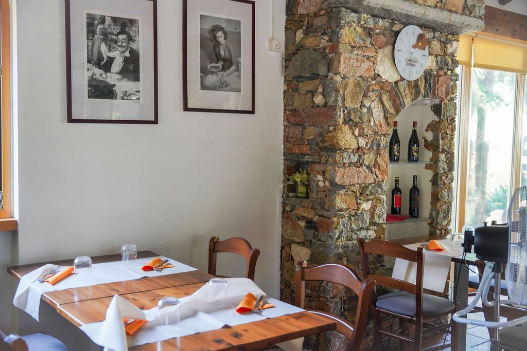 Accogliente sala da pranzo del ristorante con tavoli in legno, quadri incorniciati alle pareti e una parete decorativa in pietra con specchio.