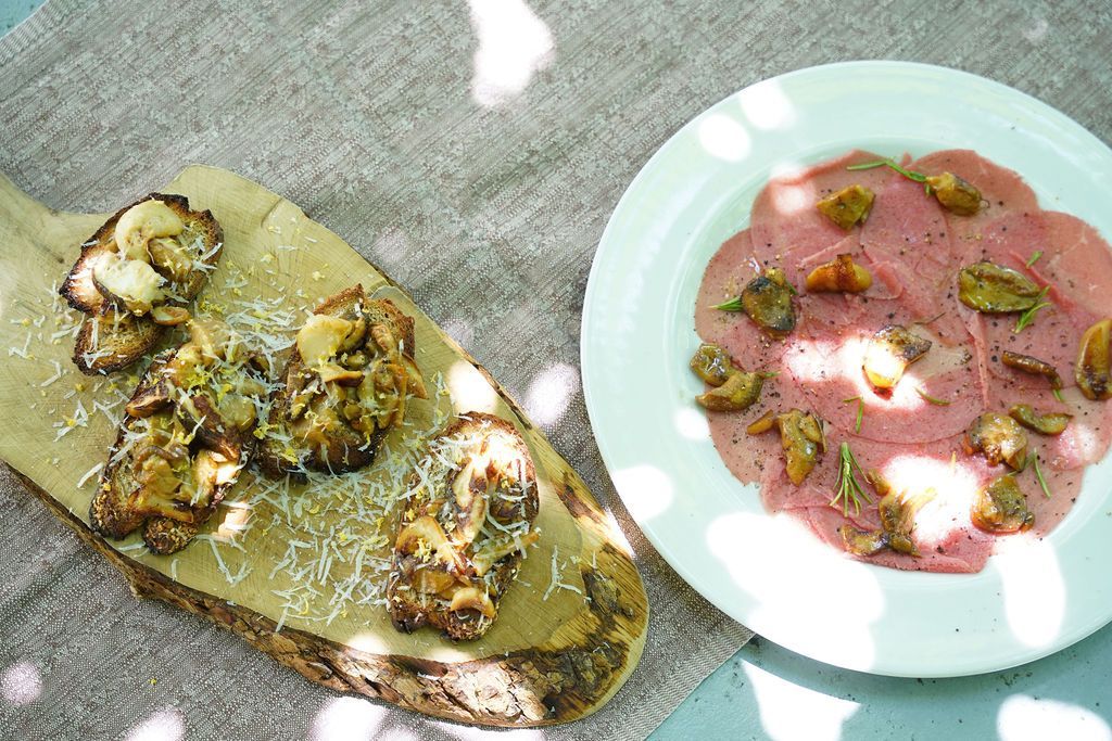 Piatto di frutti di mare con patatine fritte, gamberi grigliati, capesante nel guscio e spicchi di limone su un piatto bianco.