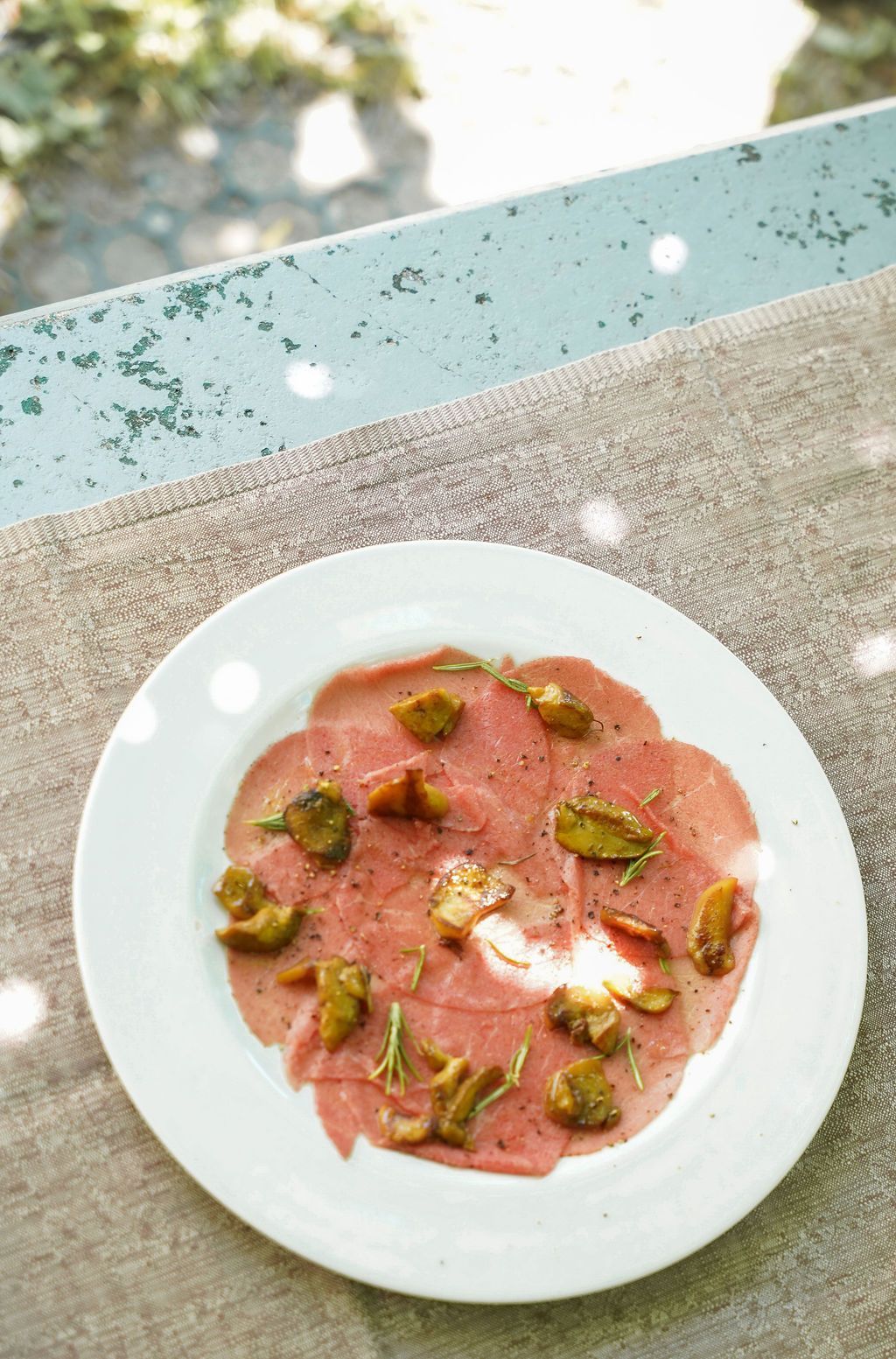 Una ciotola bianca di dessert rosa guarnita con noci verdi su un tavolo all'aperto.