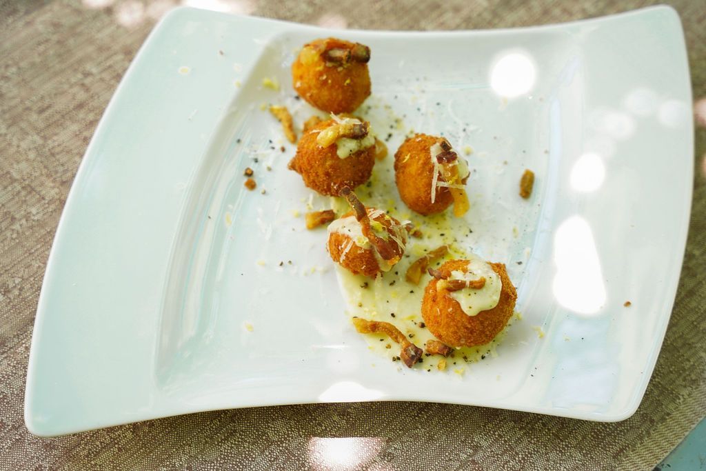 Piatto rettangolare bianco con quattro piccoli antipasti arancioni-marroni e guarnizione verde su un tavolo