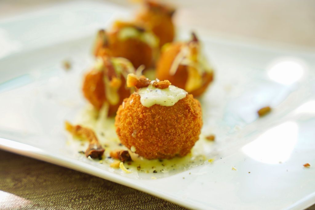 Sfere di dessert all'arancia guarnite con panna e noci su un piatto bianco.