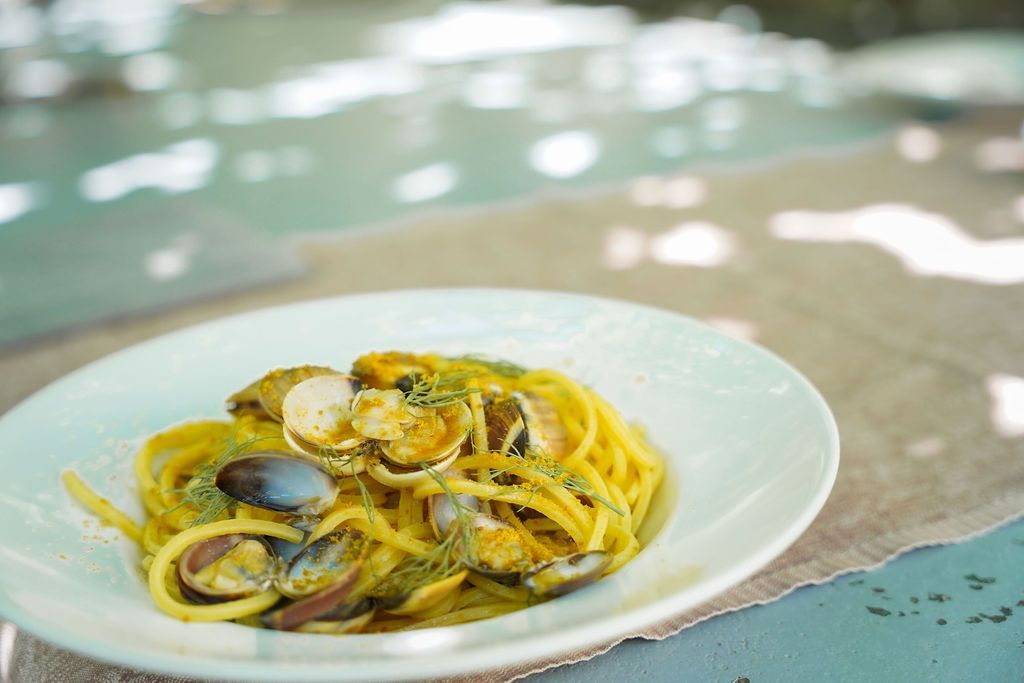 Piatto di pasta ai frutti di mare con vongole in salsa leggera su un tavolo all'aperto