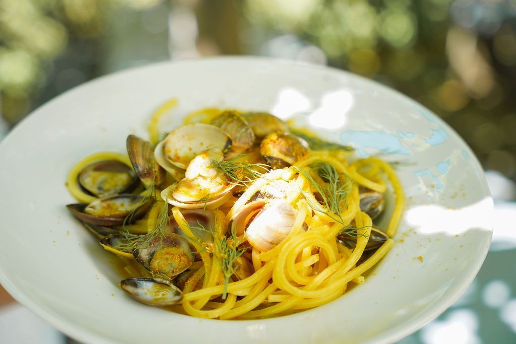 Piatto di spaghetti con vongole e guarnizione di limone su un piatto bianco all'aperto