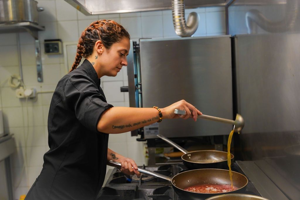 Lo chef versa la salsa in una padella in una cucina in acciaio inossidabile