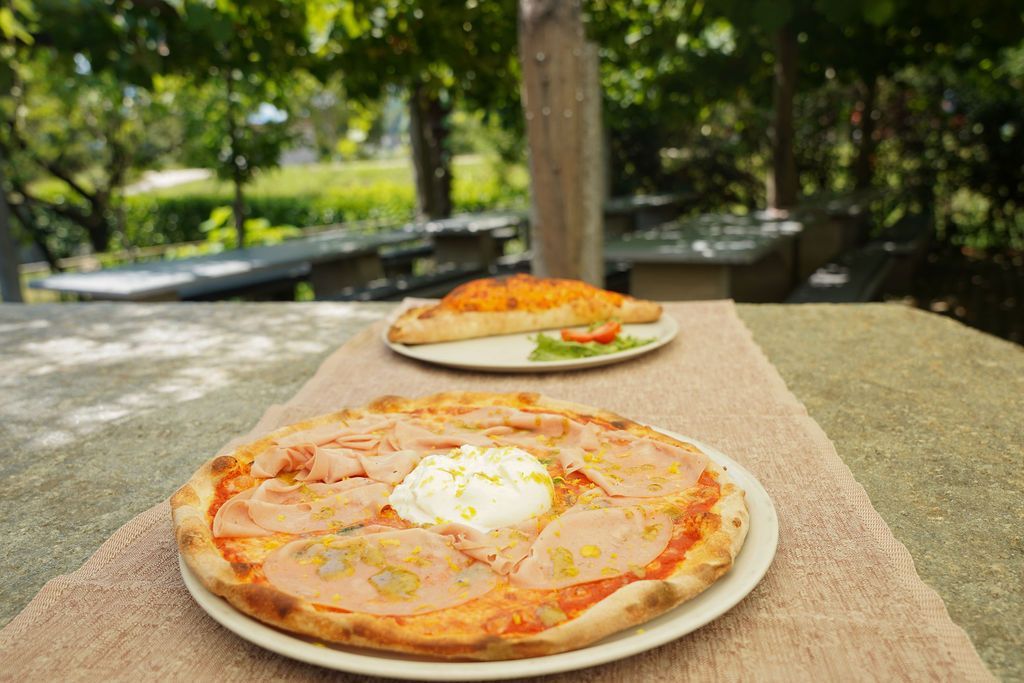 Due pizze su piatti su un tavolo all'aperto in un parco.