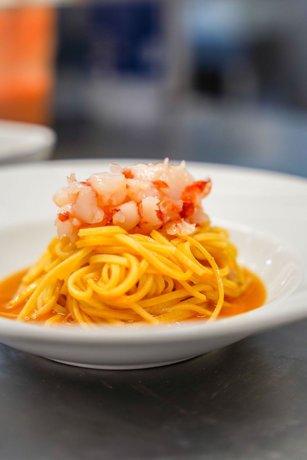 Un piatto di spaghetti al sugo d'arancia con gamberetti a dadini su un tavolo.