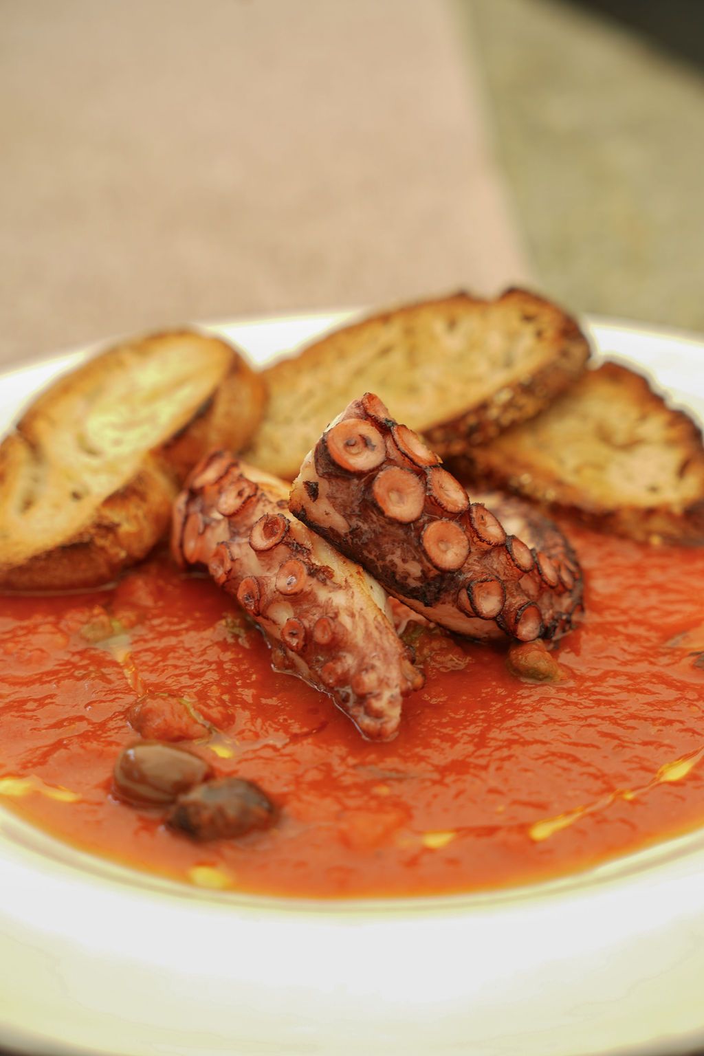 Piatto di polpo in salsa rossa con fette di pane tostato