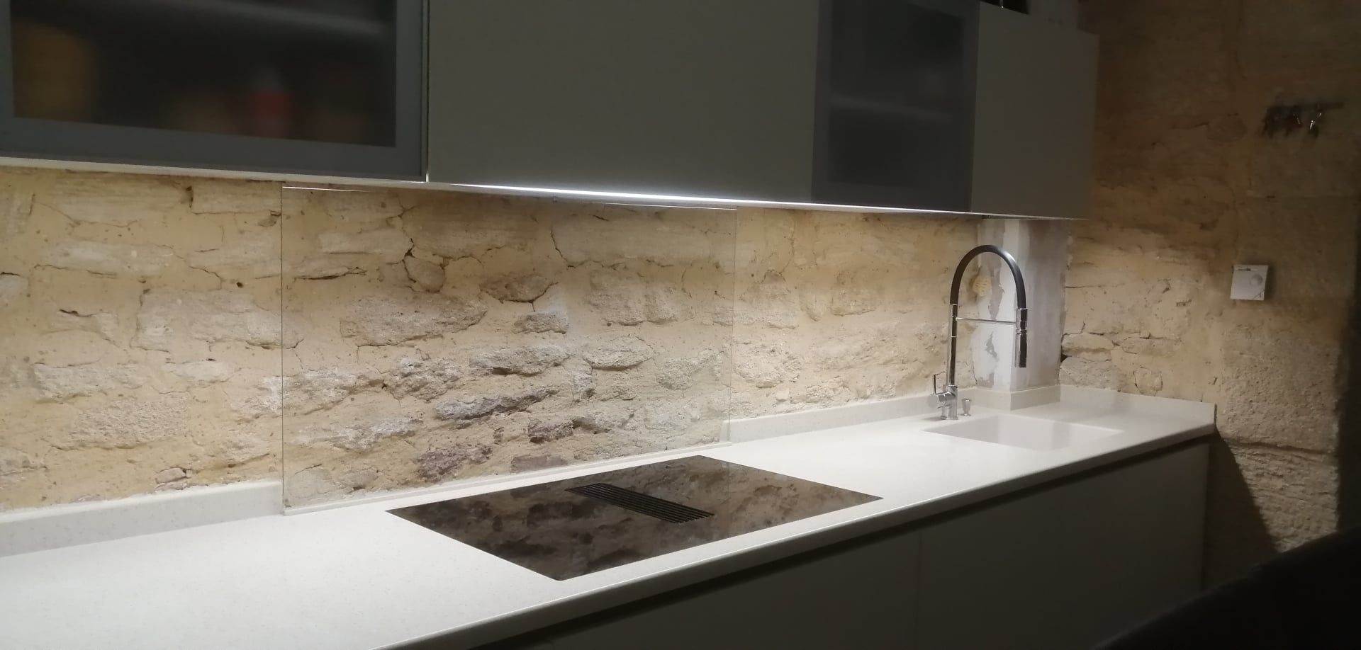Une cuisine équipée avec des murs en pierres apparentes.