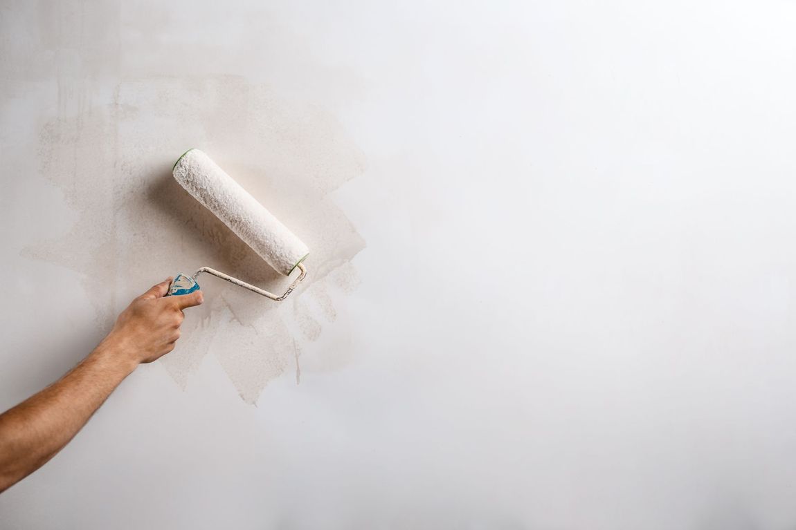 Un artisan peint un mur en blanc
