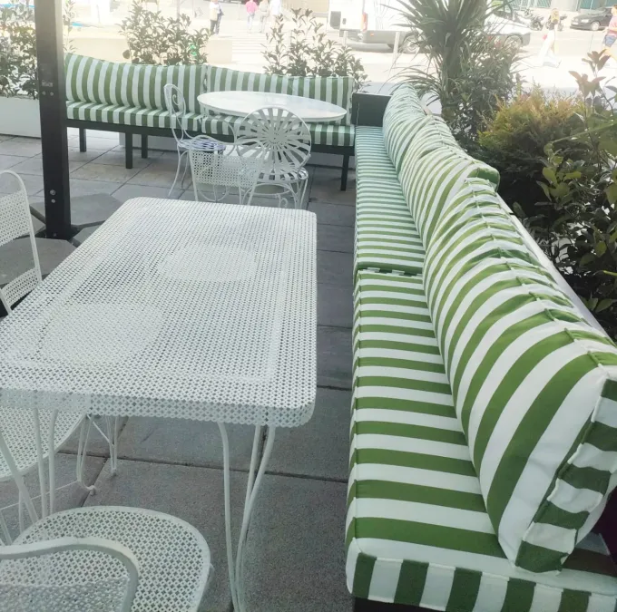 Un sofá de rayas verdes y blancas se encuentra junto a una mesa blanca.