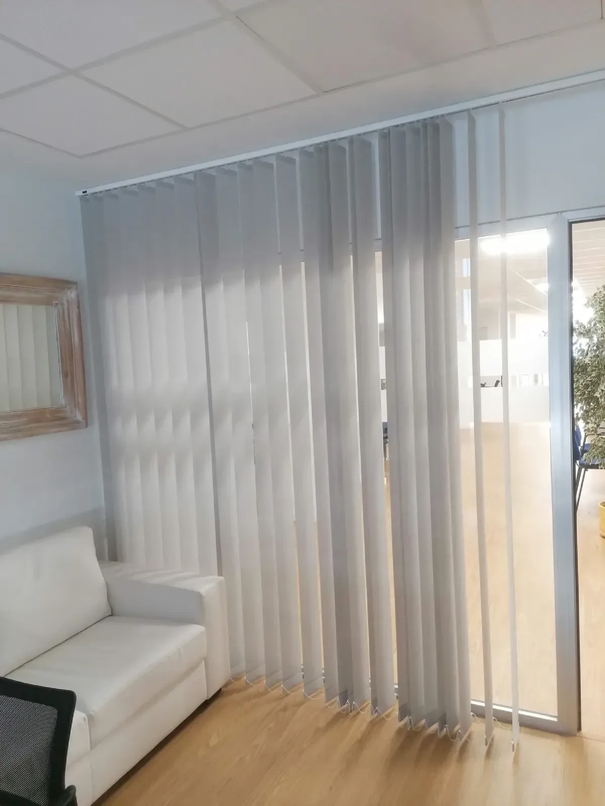 Una sala de estar con un sofá y persianas en las ventanas.