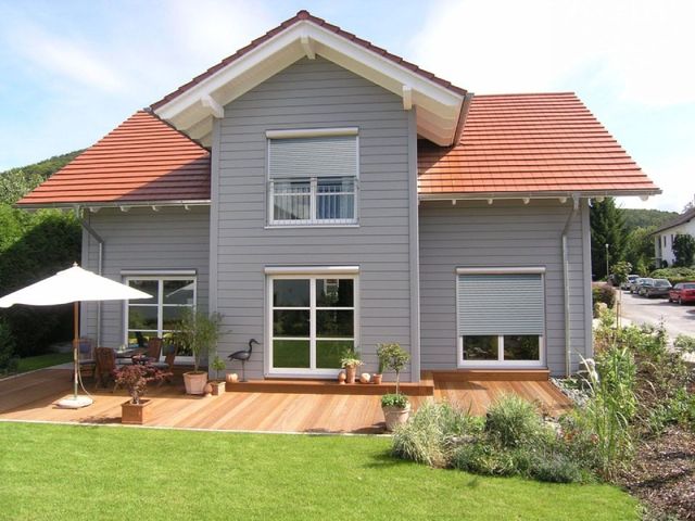 Brenig Instandsetzungs GmbH – graues Haus mit Holzterrasse und Wiese