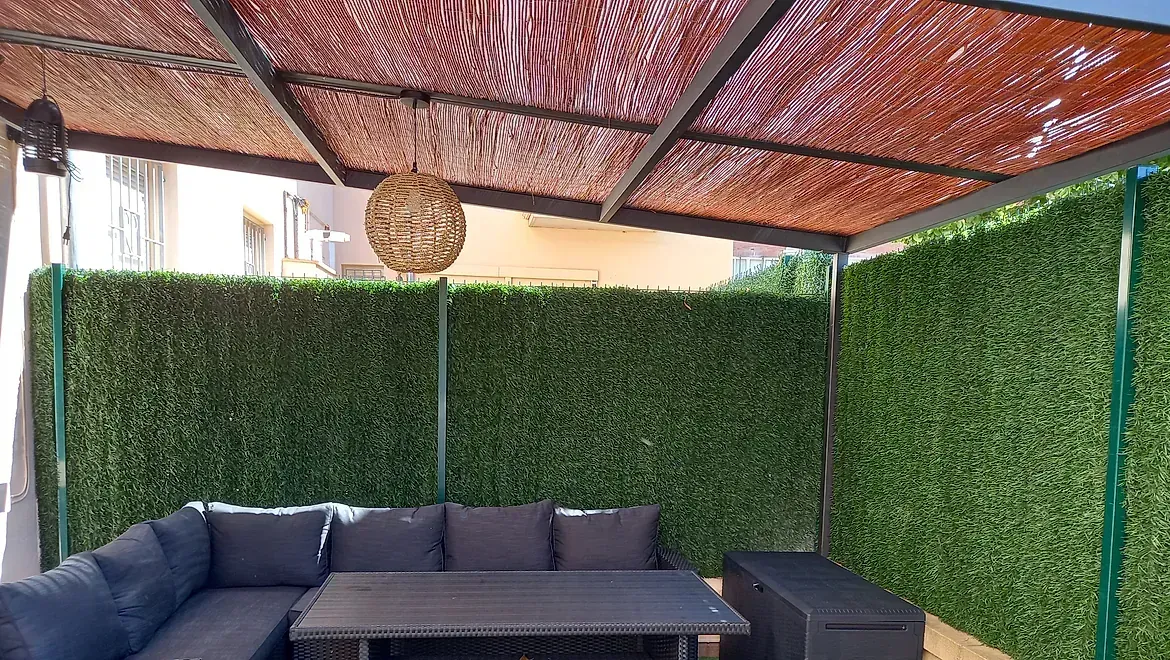 Un patio con un sofá y una mesa bajo un dosel.