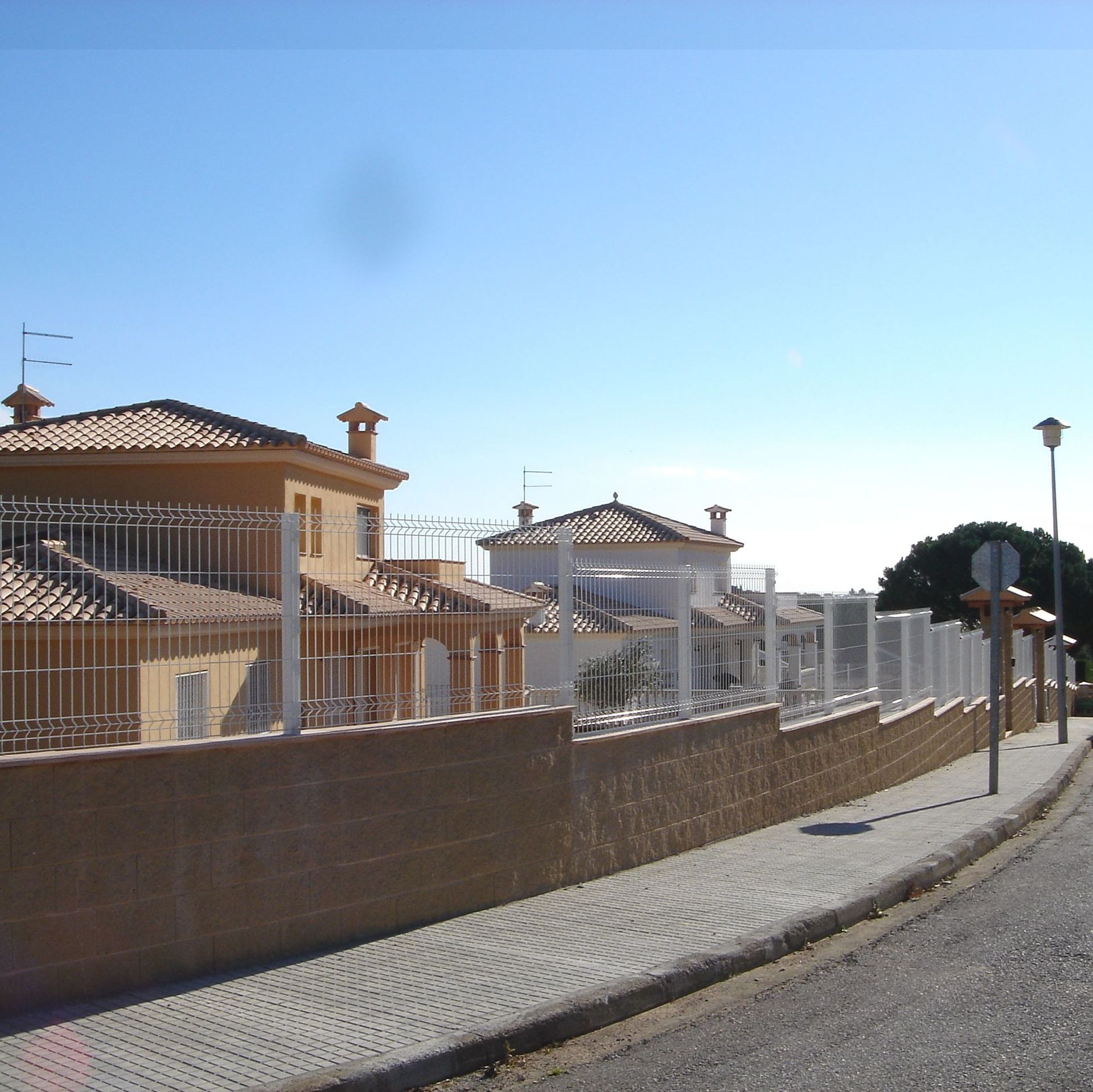 Una valla rodea una hilera de casas en un día soleado