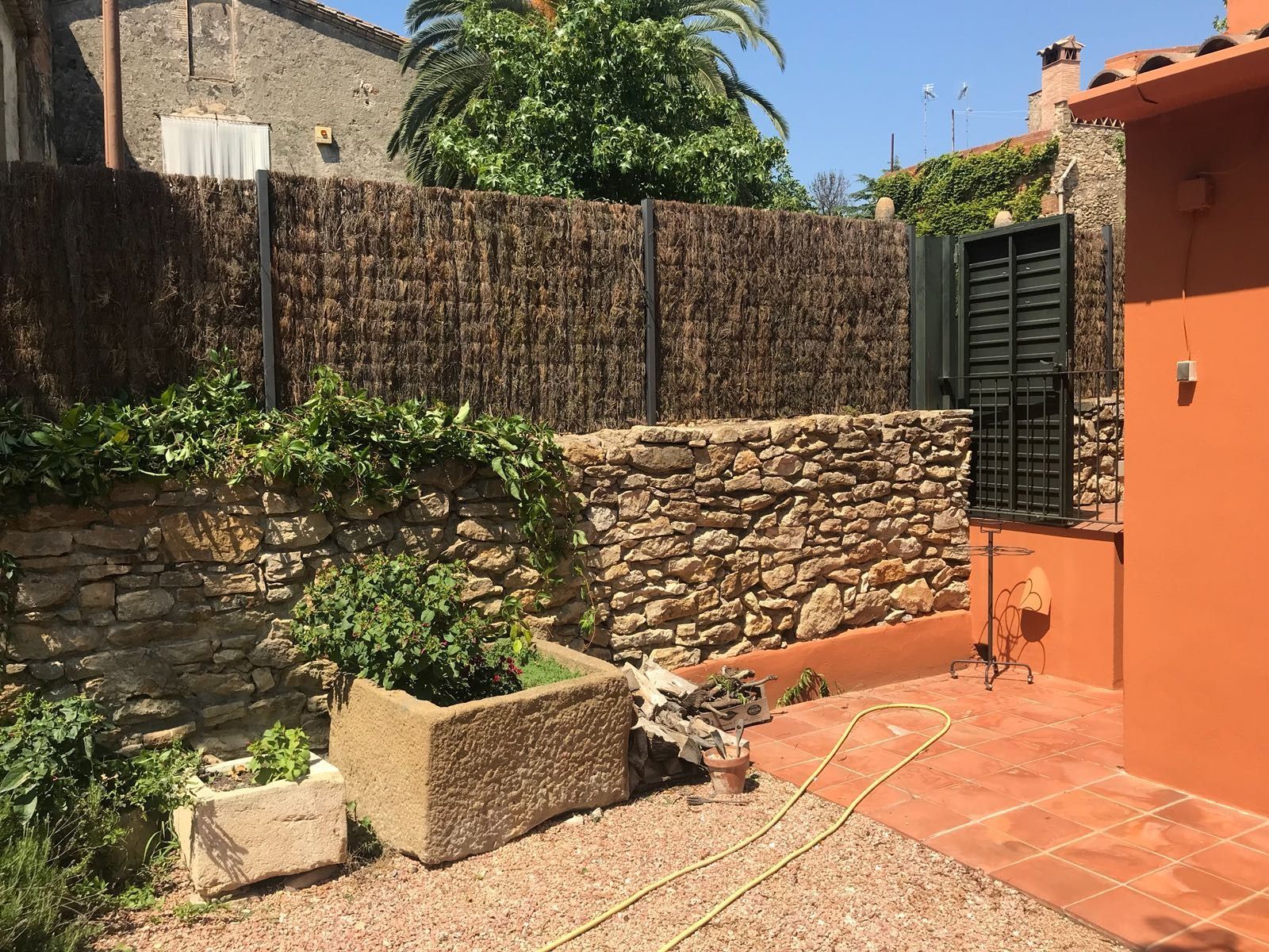 Un muro de piedra con una valla y una jardinera delante.