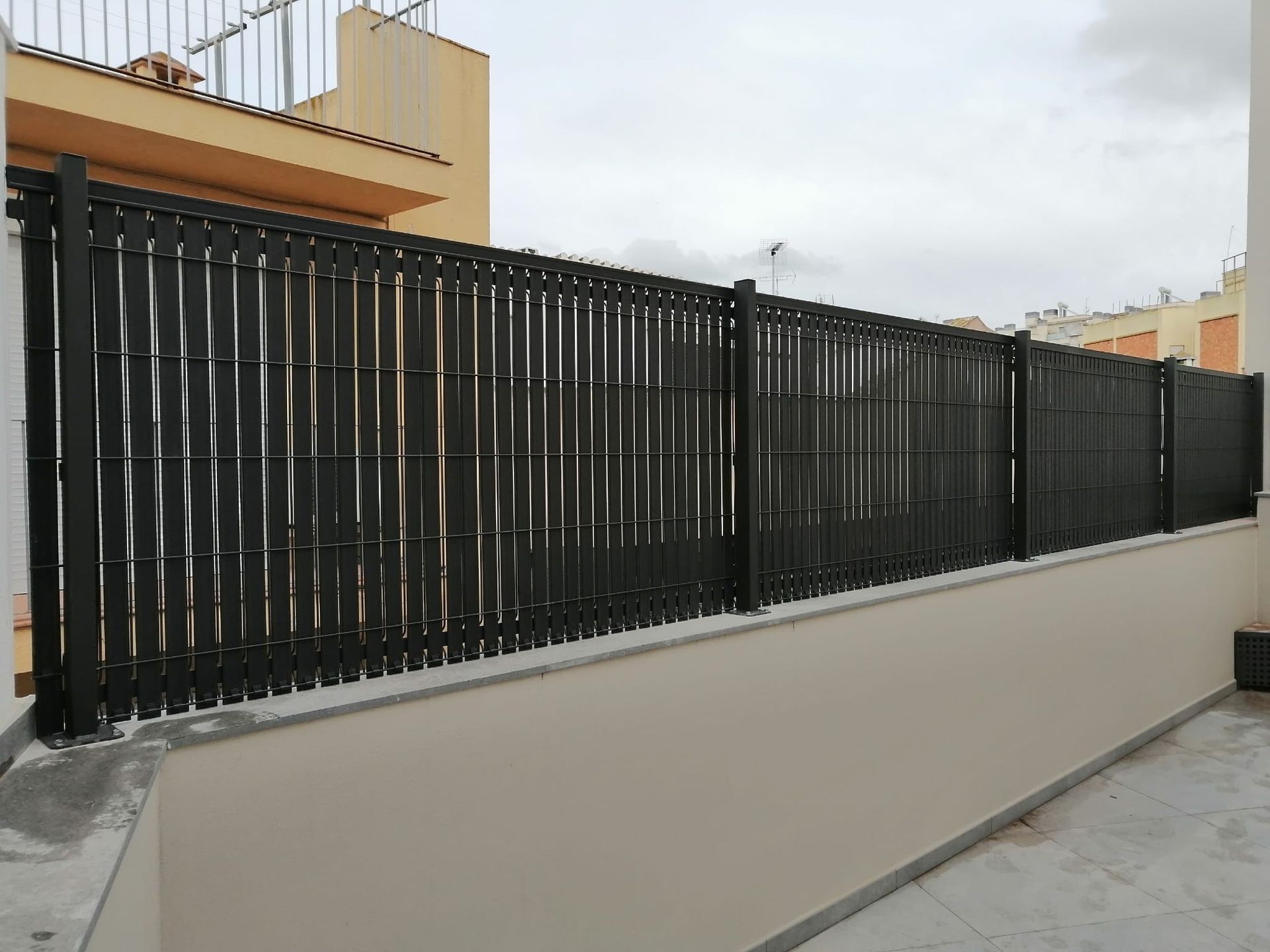 Una valla negra está sentada al costado de un edificio.